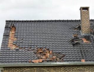 A storn has damaged a house and caused roof tiles to become dislodged.
